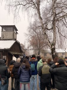 Students at the former main gate to Auschwitz I.